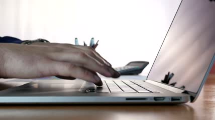 一名男子在办公桌上用笔记本电脑打字视频