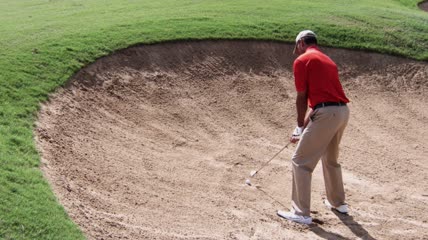 沙地用力击打高尔夫球