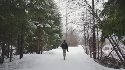 摄影师走在森林里的雪地上实拍