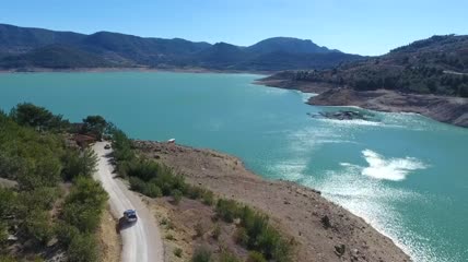 在湖边的路上行驶的汽车实拍