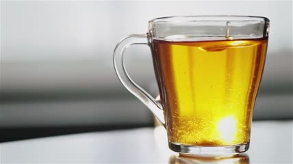 在透明玻璃茶杯中用勺子搅拌糖特写实拍