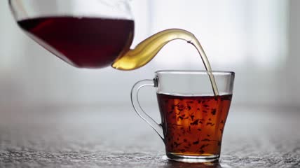茶壶将茶倒入透明玻璃杯中特写实拍