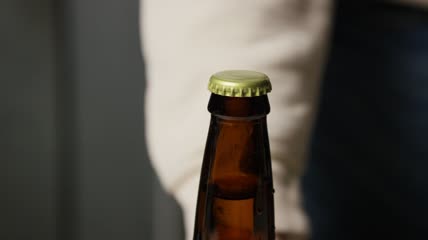 将啤酒盖添加并密封到瓶子上特写实拍