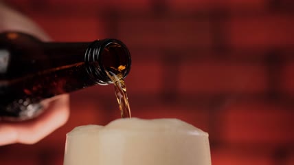 泡沫溢出来时把啤酒倒进玻璃杯里特写
