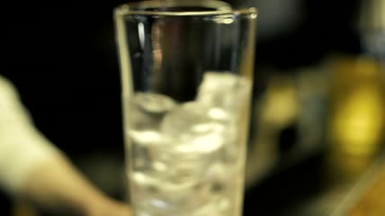 调酒师在玻璃杯里搅拌冰块特写实拍