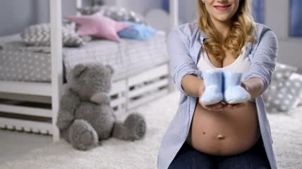 抱着婴儿鞋的孕妇特写实拍