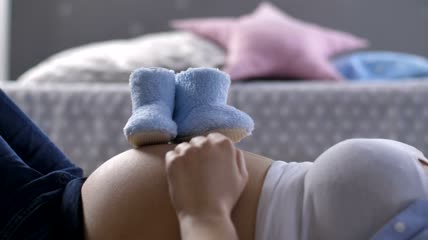 一名妇女放着婴儿鞋躺下特写实拍