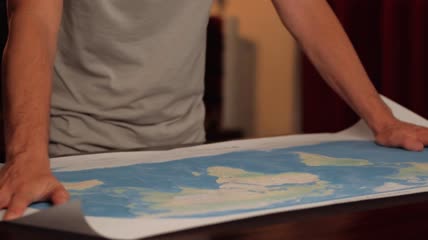 在桌子上展开世界地图特写实拍