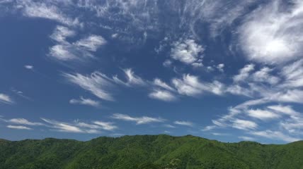 云朵掠过一座绿树成荫的山峰实拍