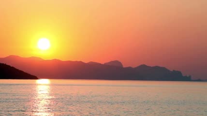 从海滩上看美丽日落倒映在海面上
