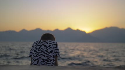 孤独的男孩坐在海边特写实拍