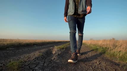 一名不明身份的男子走在土路上特写实拍