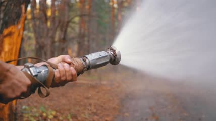 树林里男子拿着消防水龙灭火特写