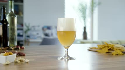 把啤酒倒进厨房桌子上的玻璃杯里特写