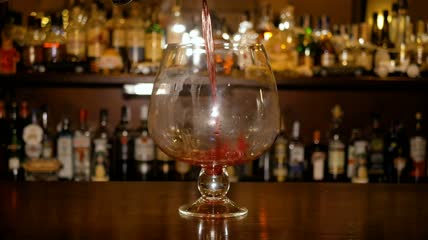 热酒倒入吧台柜上的大玻璃杯中特写