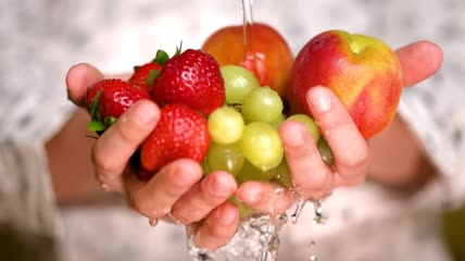 手捧冲洗草莓、苹果和葡萄特写