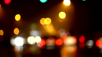 开车行驶在夜晚霓虹灯光斑街道上